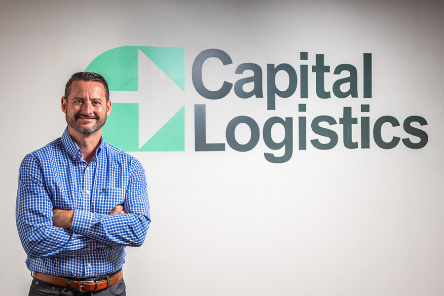 Chris Kelly standing in front of the Capital Logistics sign on the wall